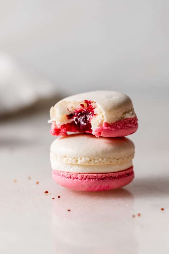 Cranberry vanilla bean French macarons filled with creamy vanilla buttercream and cranberry jam.