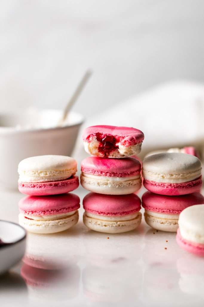 Cranberry vanilla macarons filled with vanilla buttercream and cranberry jam. A sweet and tart festive holiday macaron combo, fitting for Thanksgiving and Christmas. Naturally gluten free with a dairy free option included.