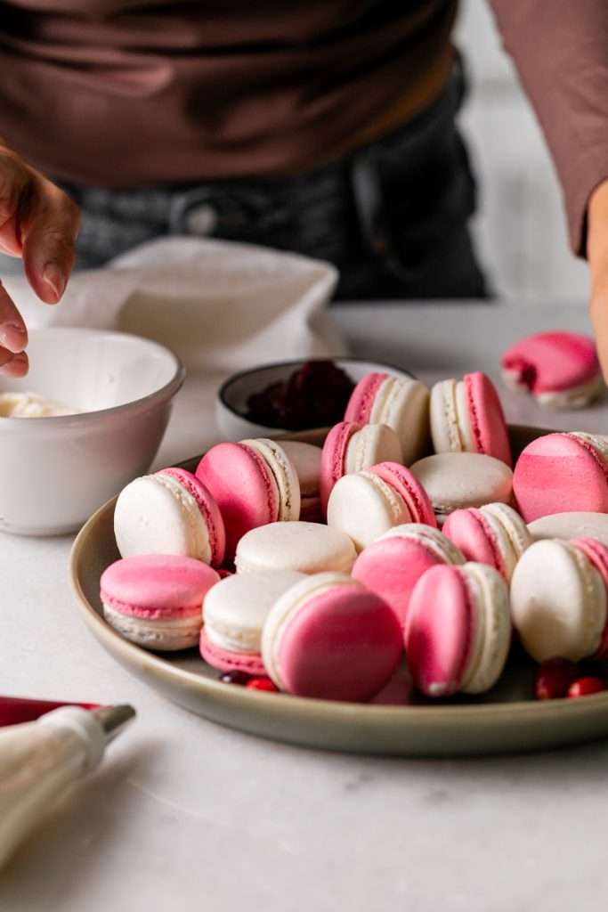 Cranberry vanilla bean French macarons filled with creamy vanilla buttercream and cranberry jam.