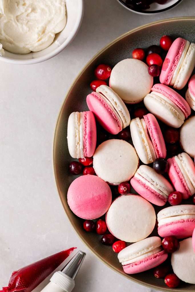 Cranberry vanilla bean French macarons filled with creamy vanilla buttercream and cranberry jam.