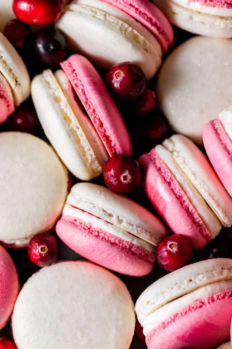 Cranberry vanilla macarons filled with vanilla buttercream and cranberry jam. A sweet and tart festive holiday macaron combo, fitting for Thanksgiving and Christmas. Naturally gluten free with a dairy free option included.