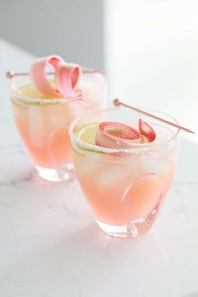 Refreshing rhubarb paloma cocktail with tequila, grapefruit, juice and lime, garnished with rhubarb ribbons and citrus slices.