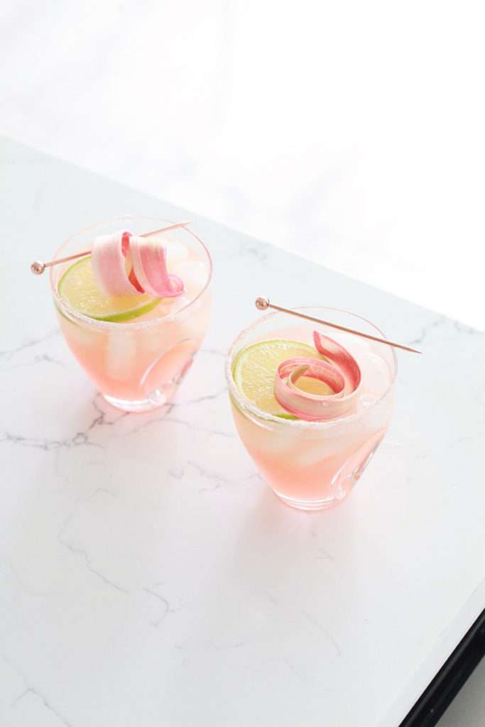 Refreshing rhubarb paloma cocktail with tequila, grapefruit, juice and lime, garnished with rhubarb ribbons and citrus slices.