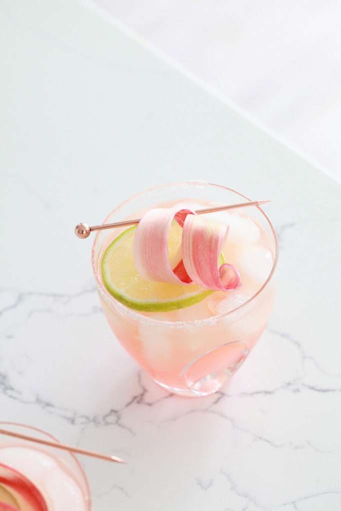 Refreshing rhubarb paloma cocktail with tequila, grapefruit, juice and lime, garnished with rhubarb ribbons and citrus slices.
