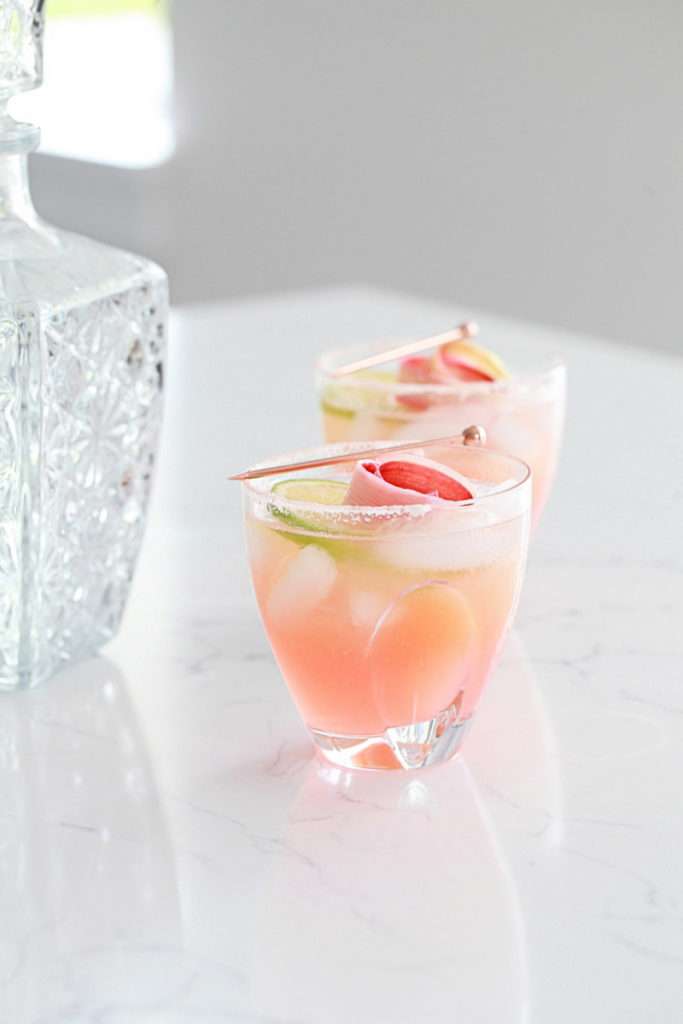 Refreshing rhubarb paloma cocktail with tequila, grapefruit, juice and lime, garnished with rhubarb ribbons and citrus slices.