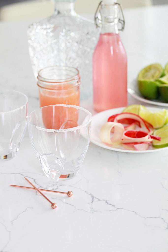 Refreshing rhubarb paloma cocktail with tequila, grapefruit, juice and lime, garnished with rhubarb ribbons and citrus slices.