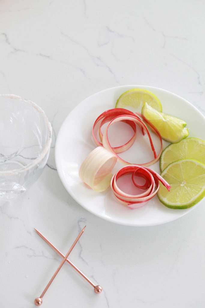 Refreshing rhubarb paloma cocktail with tequila, grapefruit, juice and lime, garnished with rhubarb ribbons and citrus slices.