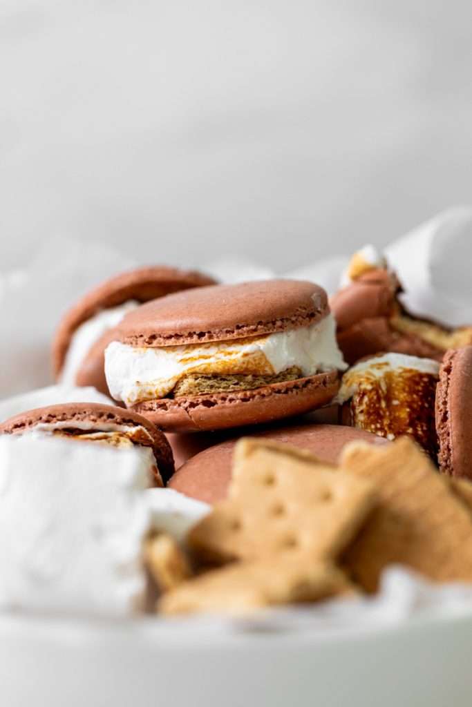 Don't let summer come to an end without making a batch of these S'mores macarons. Complete with chocolate macaron shells, homemade marshamallows, graham crackers and dark chocolate, they are the ultimate s'mores dessert for the season! Dairy free and gluten free option included.