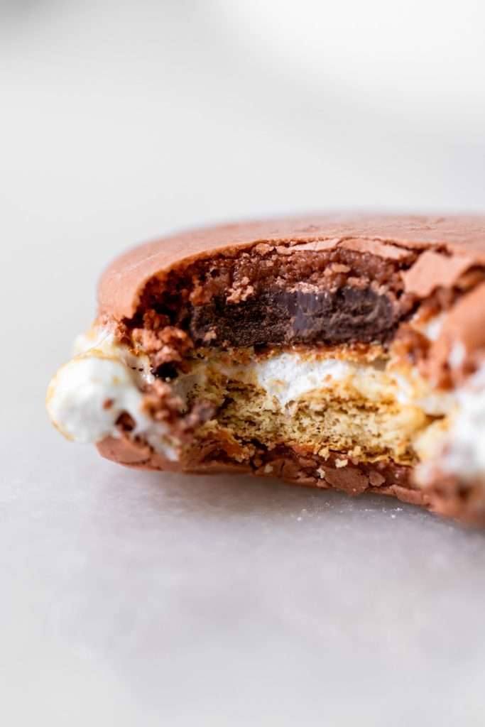 Don't let summer come to an end without making a batch of these S'mores macarons. Complete with chocolate macaron shells, homemade marshamallows, graham crackers and dark chocolate, they are the ultimate s'mores dessert for the season! Dairy free and gluten free option included.