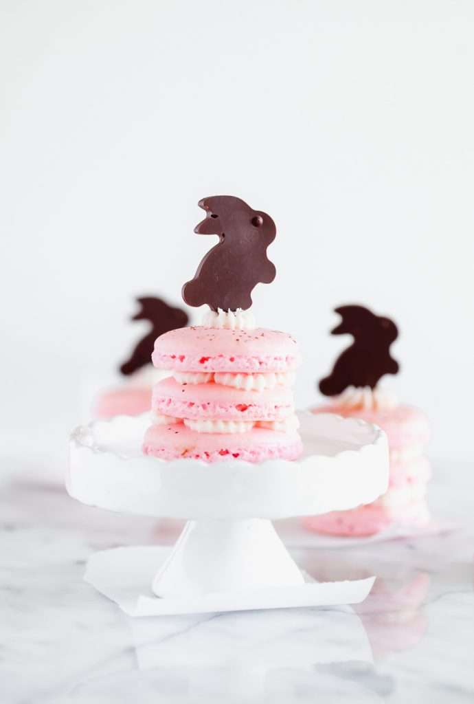Chocolate bunny macarons stacks, 3 shells high, layered with speckled macaron shells, vanilla frosting and finished with cute chocolate bunnies. Perfect for your Easter Sunday brunch dessert menus.