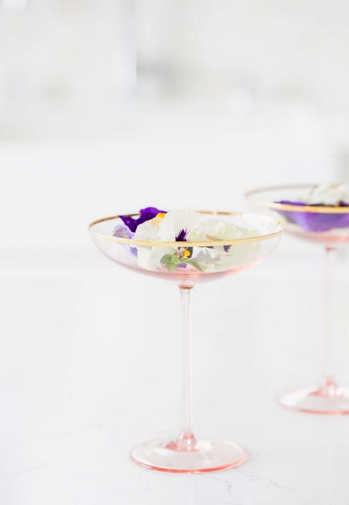 Floral spring champagne cocktail made with cream de Violette, lemon, and champagne, served in coupe glasses with flower garnish.