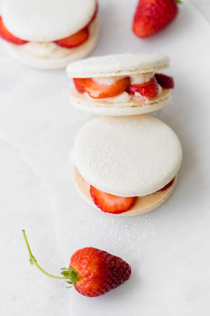Strawberry shortcake macarons recipe, made with French macaron shells, fresh strawberries and vanilla whip frosting. Dairy and gluten free