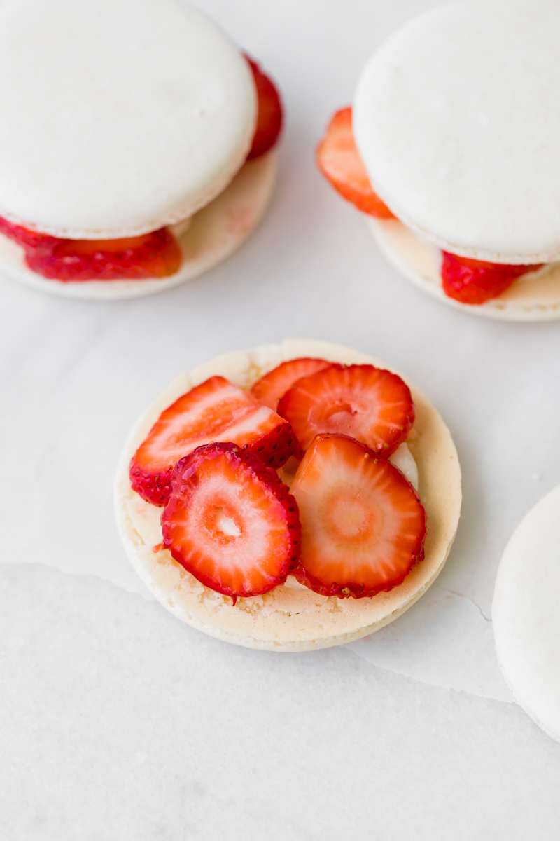 Strawberry shortcake macarons recipe, made with French macaron shells, fresh strawberries and vanilla whip frosting. Dairy and gluten free
