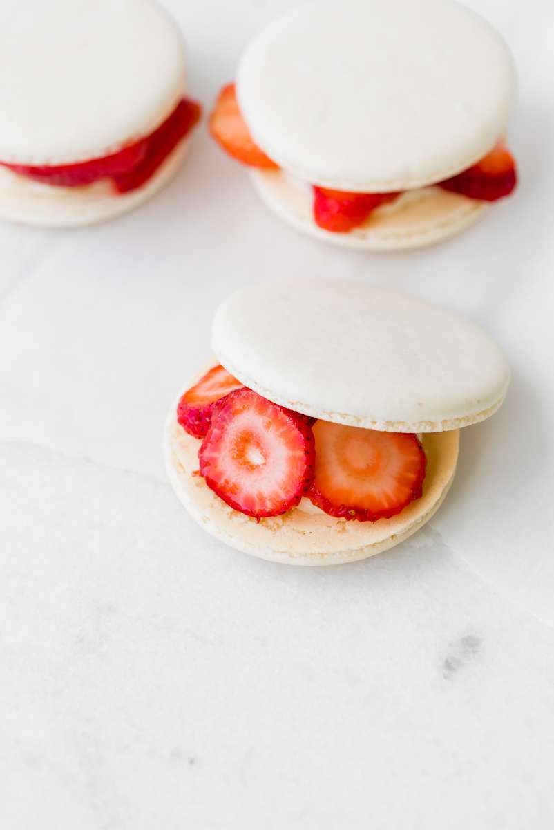 Strawberry shortcake macarons recipe, made with French macaron shells, fresh strawberries and vanilla whip frosting. Dairy and gluten free