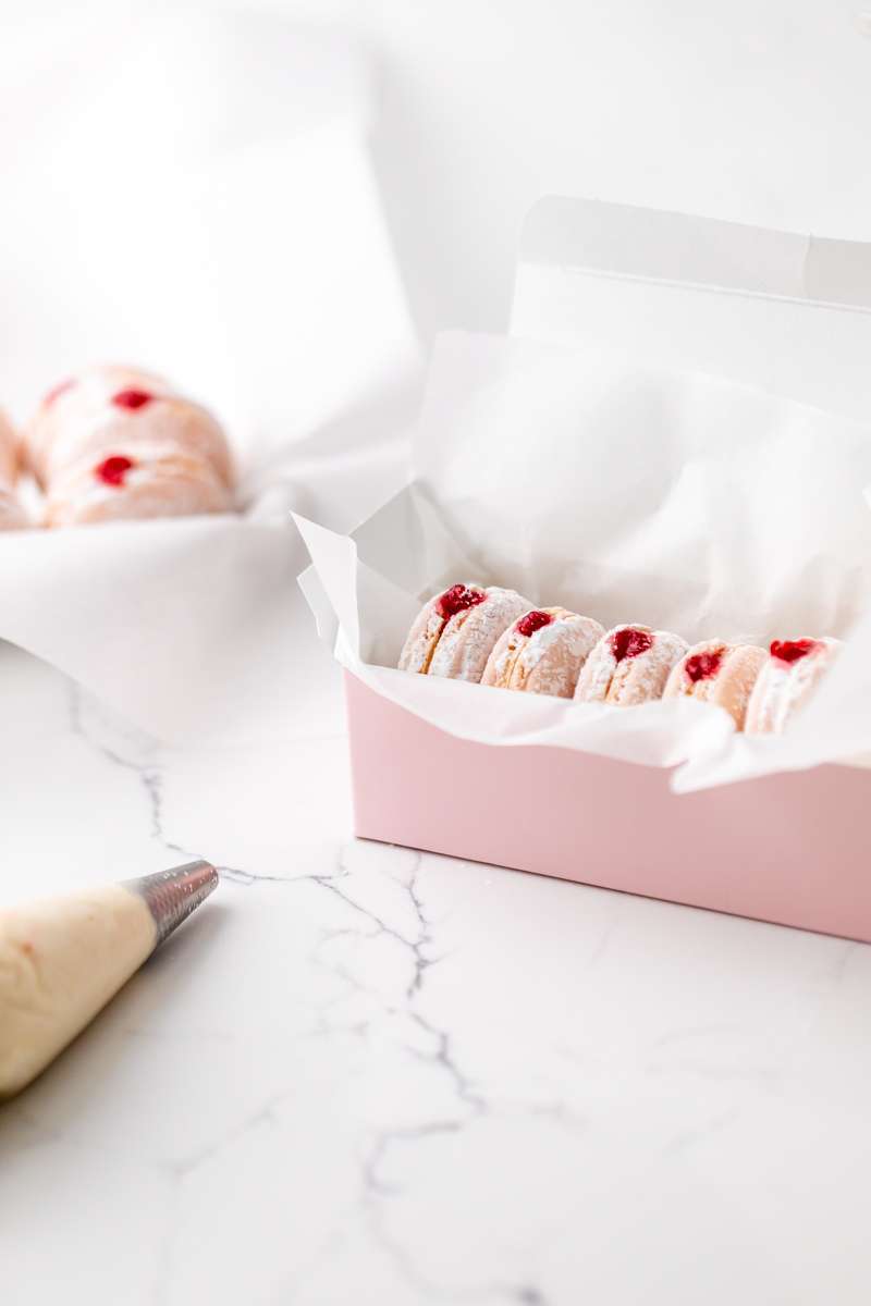 jelly donut flavored French macarons made with donut frosting, homemade raspberry jam and confectioner's sugar