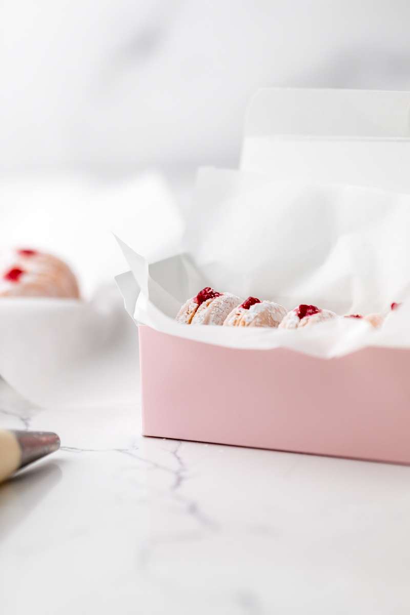 jelly donut flavored French macarons made with donut frosting, homemade raspberry jam and confectioner's sugar