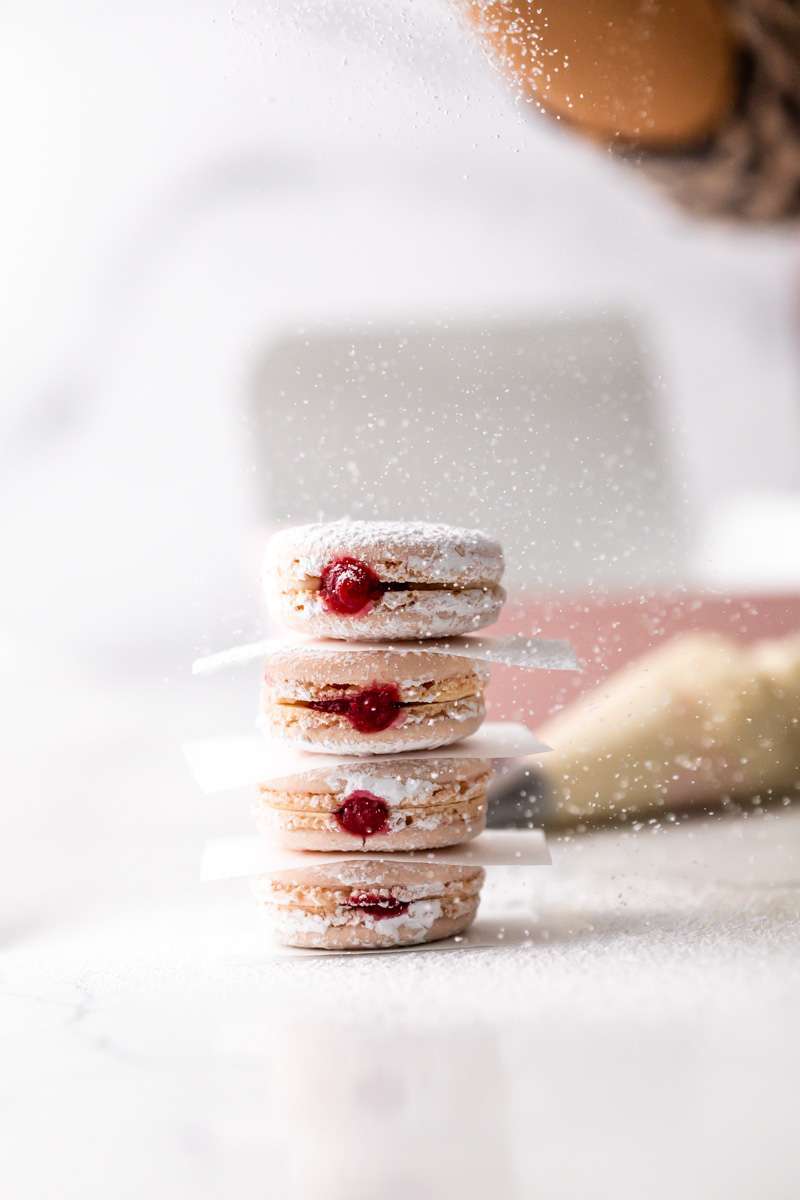 jelly donut flavored French macarons made with donut frosting, homemade raspberry jam and confectioner's sugar