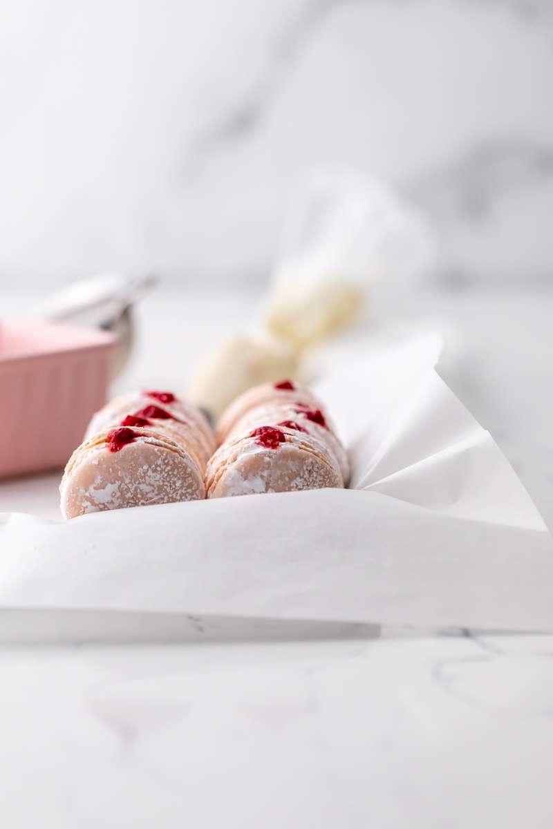 jelly donut flavored French macarons made with donut frosting, homemade raspberry jam and confectioner's sugar