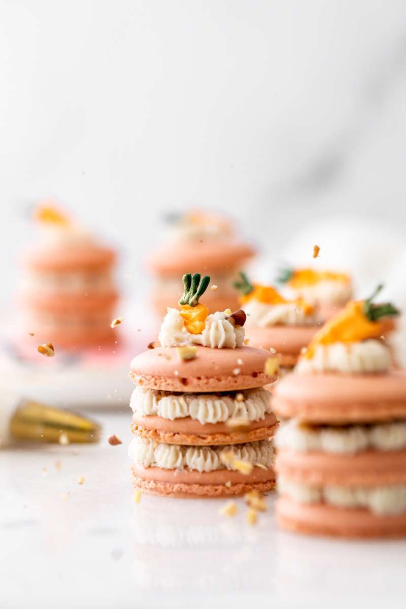 Carrot cake macaron stacks made with cinnamon frosting and carrot cake filling. Decorated with carrot icing decorations. Dairy & Gluten Free and perfect for Easter dessert menus!