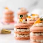 Carrot cake macaron stacks made with cinnamon frosting and carrot cake filling. Decorated with carrot icing decorations. Dairy & Gluten Free and perfect for Easter dessert menus!