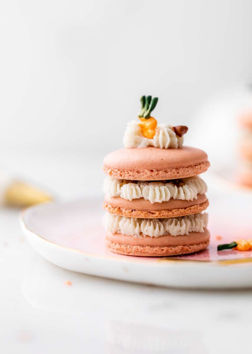 Carrot cake macaron stacks made with cinnamon frosting and carrot cake filling. Decorated with carrot icing decorations. Dairy & Gluten Free and perfect for Easter dessert menus!