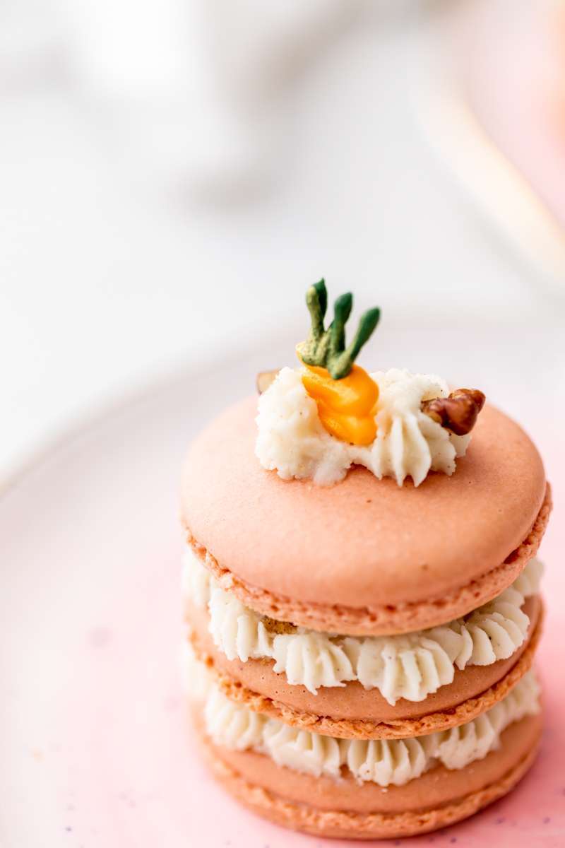 Carrot cake macaron stacks made with cinnamon frosting and carrot cake filling. Decorated with carrot icing decorations. Dairy & Gluten Free and perfect for Easter dessert menus!