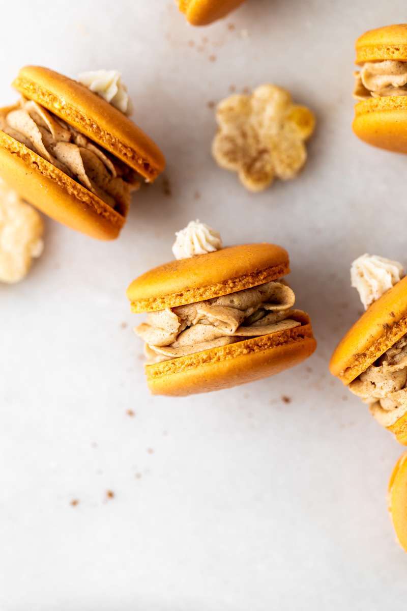 Pumpkin pie flavored French macarons, complete with pumpkin pie frosting, pie crust center, and a dollop vanilla frosting on top! The perfect one bite dessert for Thanksgiving menus. Dairy free