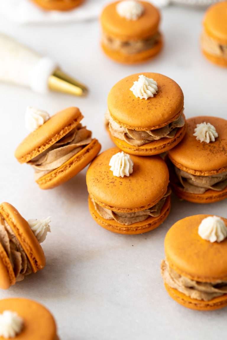Pumpkin pie flavored French macarons, complete with pumpkin pie frosting, pie crust center, and a dollop vanilla frosting on top! The perfect one bite dessert for Thanksgiving menus. Dairy free