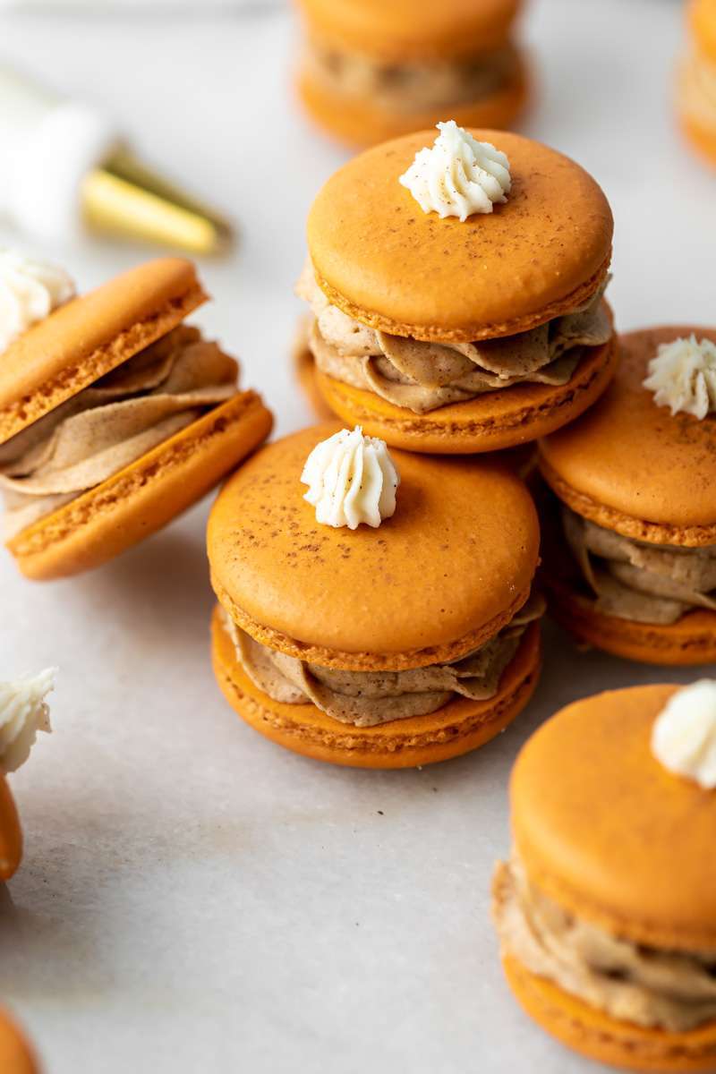 Pumpkin pie flavored French macarons, complete with pumpkin pie frosting, pie crust center, and a dollop vanilla frosting on top! The perfect one bite dessert for Thanksgiving menus. Dairy free