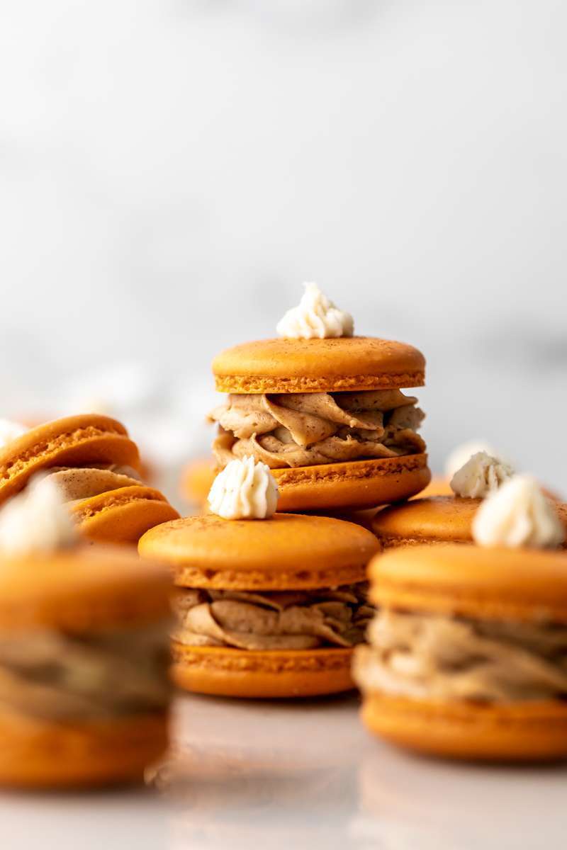 Pumpkin pie flavored French macarons, complete with pumpkin pie frosting, pie crust center, and a dollop vanilla frosting on top! The perfect one bite dessert for Thanksgiving menus. Dairy free