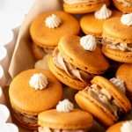 Pumpkin pie flavored French macarons, complete with pumpkin pie frosting, pie crust center, and a dollop vanilla frosting on top! The perfect one bite dessert for Thanksgiving menus. Dairy free