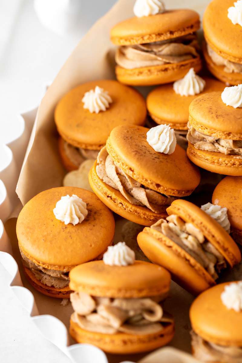Pumpkin pie flavored French macarons, complete with pumpkin pie frosting, pie crust center, and a dollop vanilla frosting on top! The perfect one bite dessert for Thanksgiving menus. Dairy free