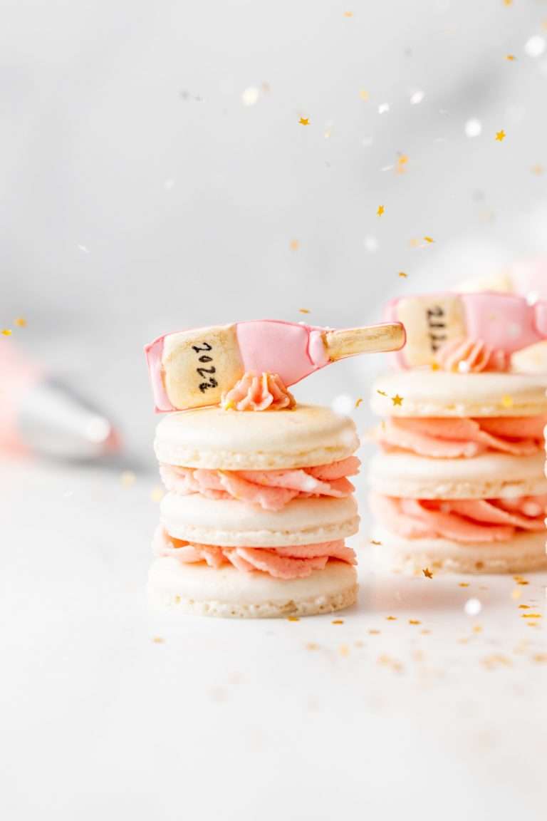 Sparkling rosé macaron stacks with champagne infused frosting. Decorated with royal icing transfers and edible glitter for a festive New Years Eve dessert!