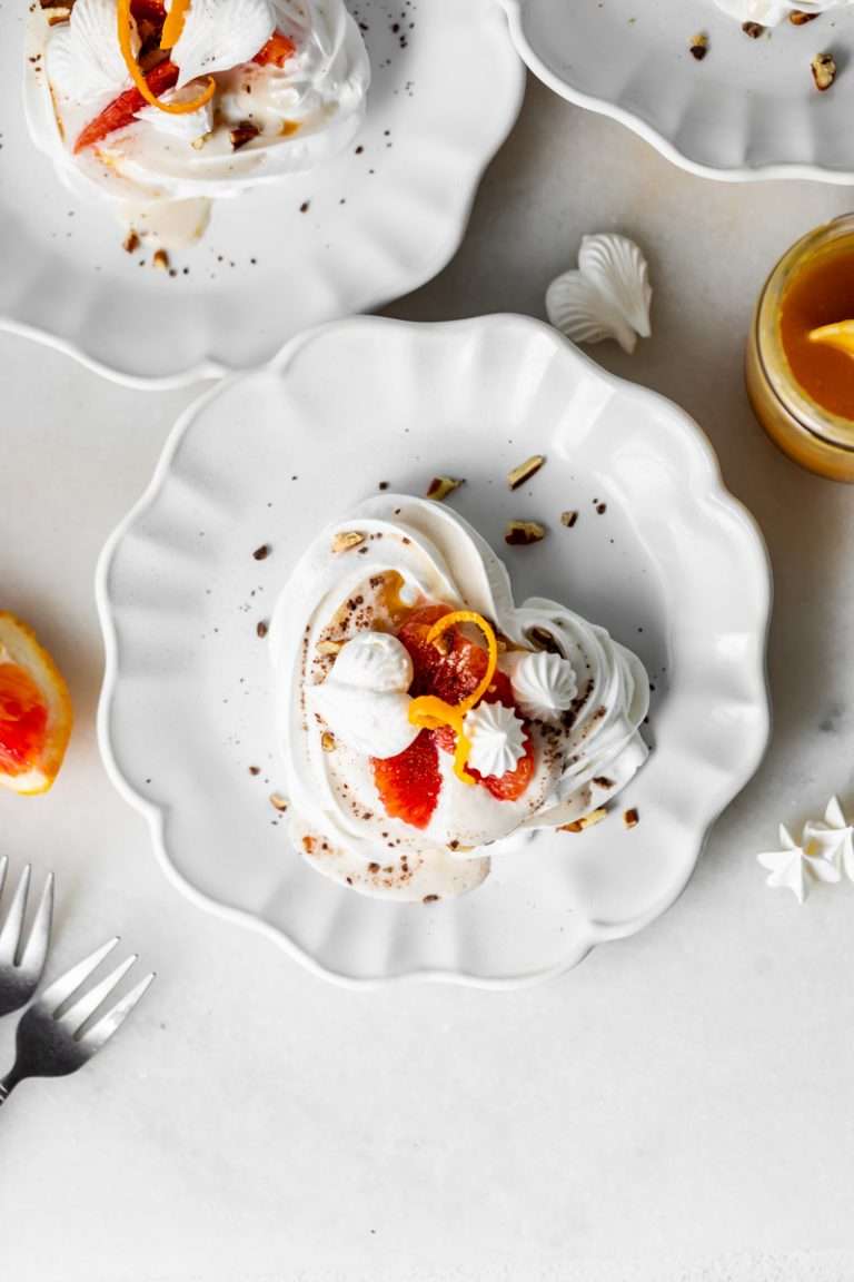 Mini pavlova hearts topped with blood orange curd, orange segments, and coconut cream. A dairy and gluten free dessert option for Valentine's Day.