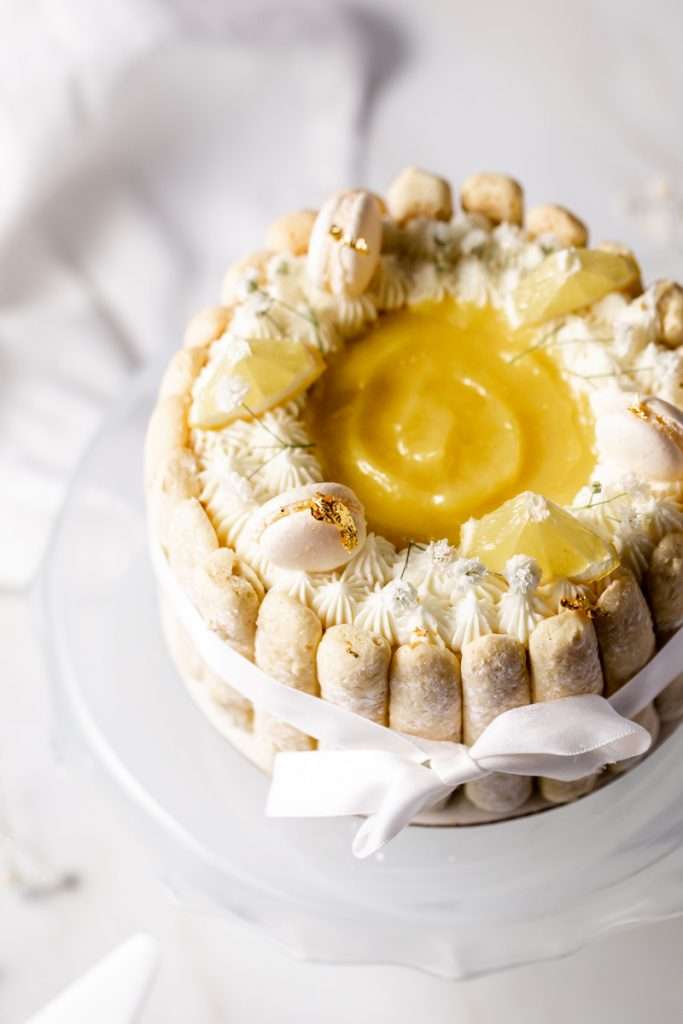 A bright and cheery lemon Charlotte cake, made with 4" macaron shells in place of sponge. Filled with lemon frosting and lemon curd. Dairy and gluten free.