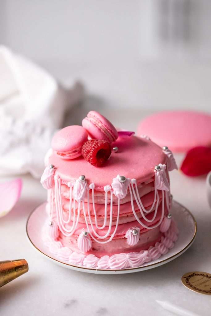 Marie Antoinette ispahan inspired macaron cake with fresh raspberries, raspberry rose frosting and royal icing decorations. The perfect party treat for birthdays and small gatherings with recipe and video included!