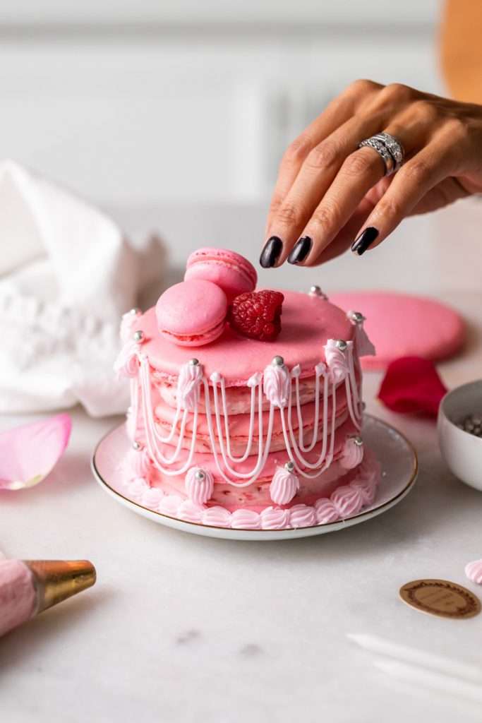 Marie Antoinette ispahan inspired macaron cake with fresh raspberries, raspberry rose frosting and royal icing decorations. The perfect party treat for birthdays and small gatherings with recipe and video included!