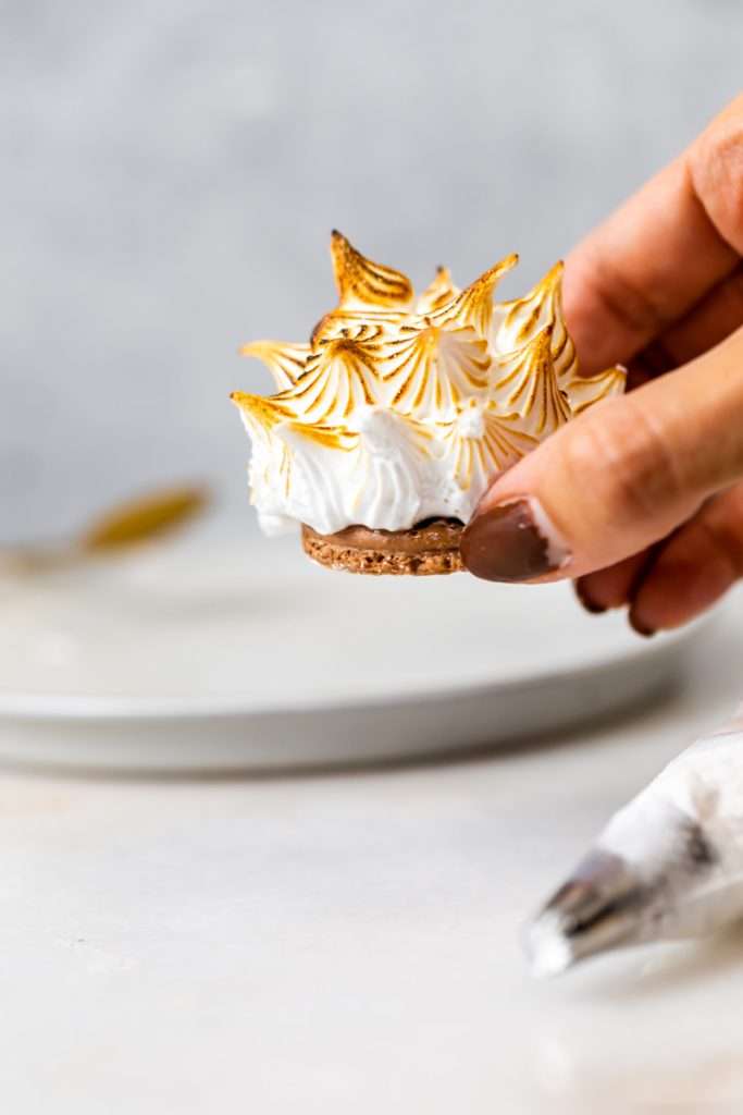 Baked Alaska Macarons, with a chocolate macaron shell base, raspberry ice cream core, topped with torched Italian meringue. A modern bite-sized spin on the classic Baked Alaska dessert. Dairy Free & Gluten Free