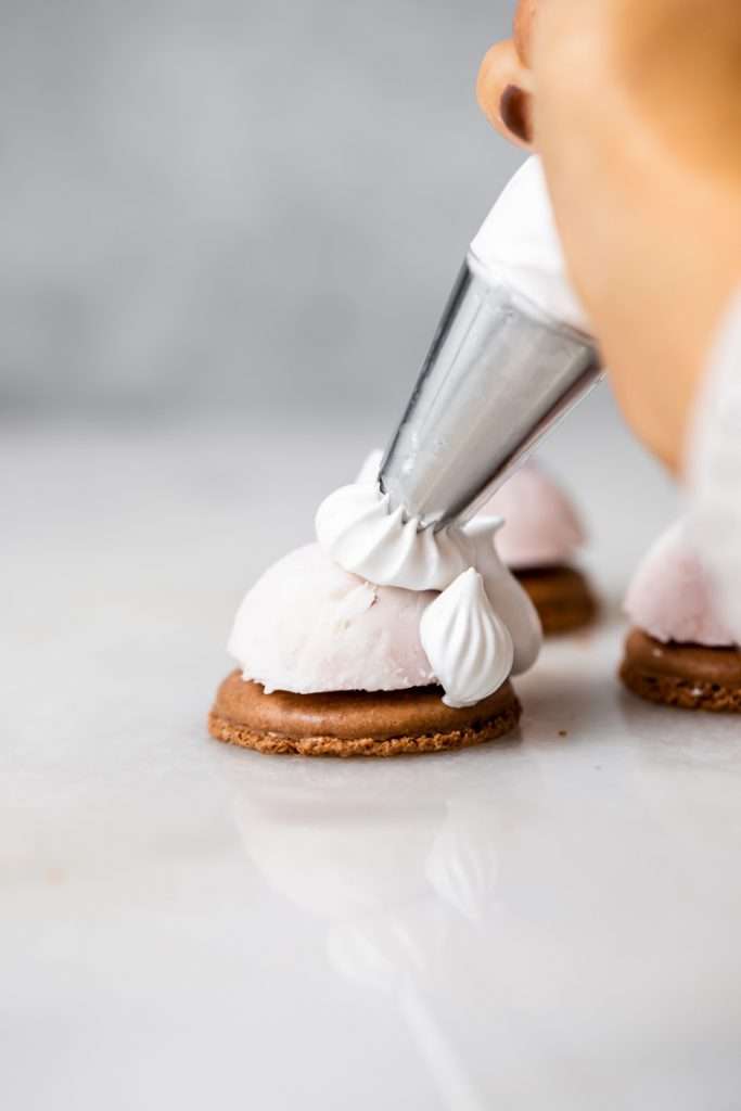 Baked Alaska Macarons, with a chocolate macaron shell base, raspberry ice cream core, topped with torched Italian meringue. A modern bite-sized spin on the classic Baked Alaska dessert. Dairy Free & Gluten Free