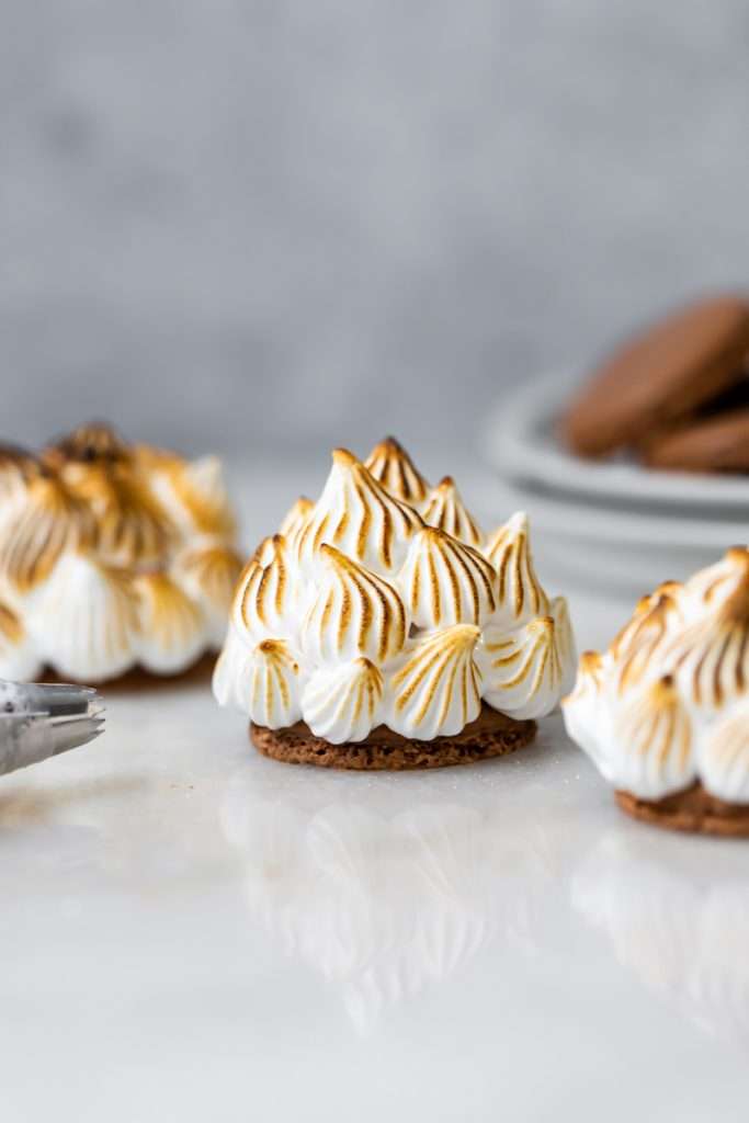Baked Alaska Macarons, with a chocolate macaron shell base, raspberry ice cream core, topped with torched Italian meringue. A modern bite-sized spin on the classic Baked Alaska dessert. Dairy Free & Gluten Free
