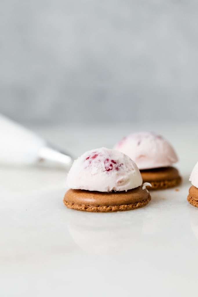Baked Alaska Macarons, with a chocolate macaron shell base, raspberry ice cream core, topped with torched Italian meringue. A modern bite-sized spin on the classic Baked Alaska dessert. Dairy Free & Gluten Free