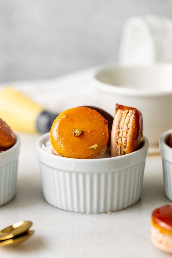 Créme brûlée macarons inspired by trendy crème brûlée donuts, complete with a creamy vanilla custard center and a crisp caramelized dipped shell. A dairy free and gluten free macaron recipe. Enjoy with tea, coffee, or champagne.