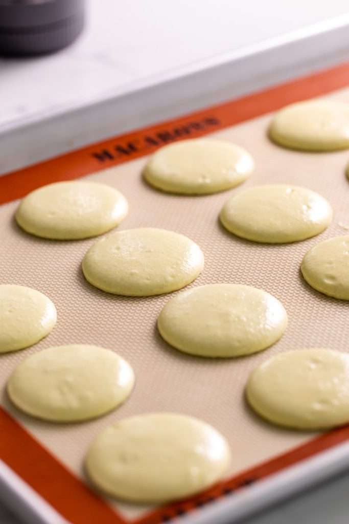 Piped yellow lemon macaron shells.