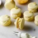 Lemon flavored French macarons filled with lemon vanilla bean frosting and lemon curd. Decorated with royal icing transfers. A dairy free and gluten free macaron recipe perfect for spring and summer.