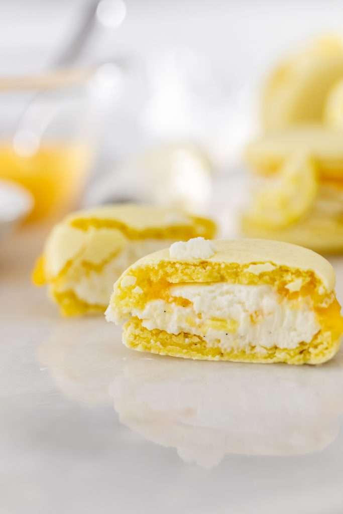 Lemon flavored French macarons filled with lemon vanilla bean frosting and lemon curd. Decorated with royal icing transfers. A dairy free and gluten free macaron recipe perfect for spring and summer.