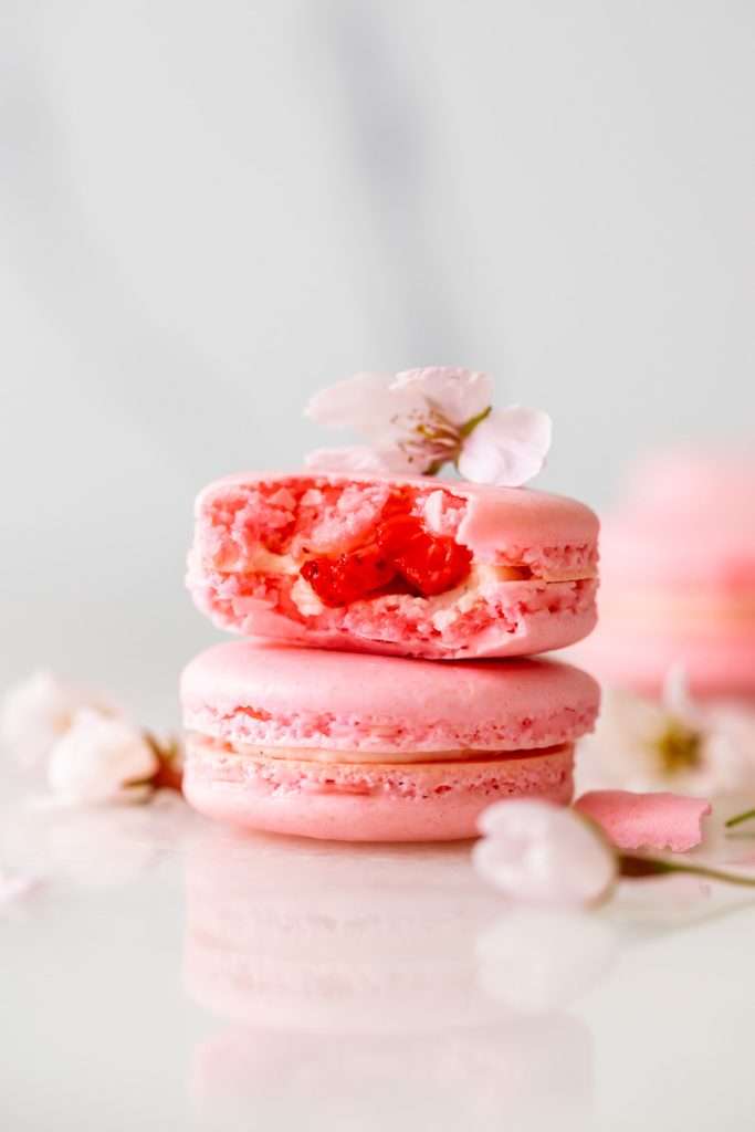 Spring macaron recipe filled with Sakura cherry blossom frosting and a fresh strawberry center. Dairy Free, Gluten Free and the perfect macaron and treat for spring.