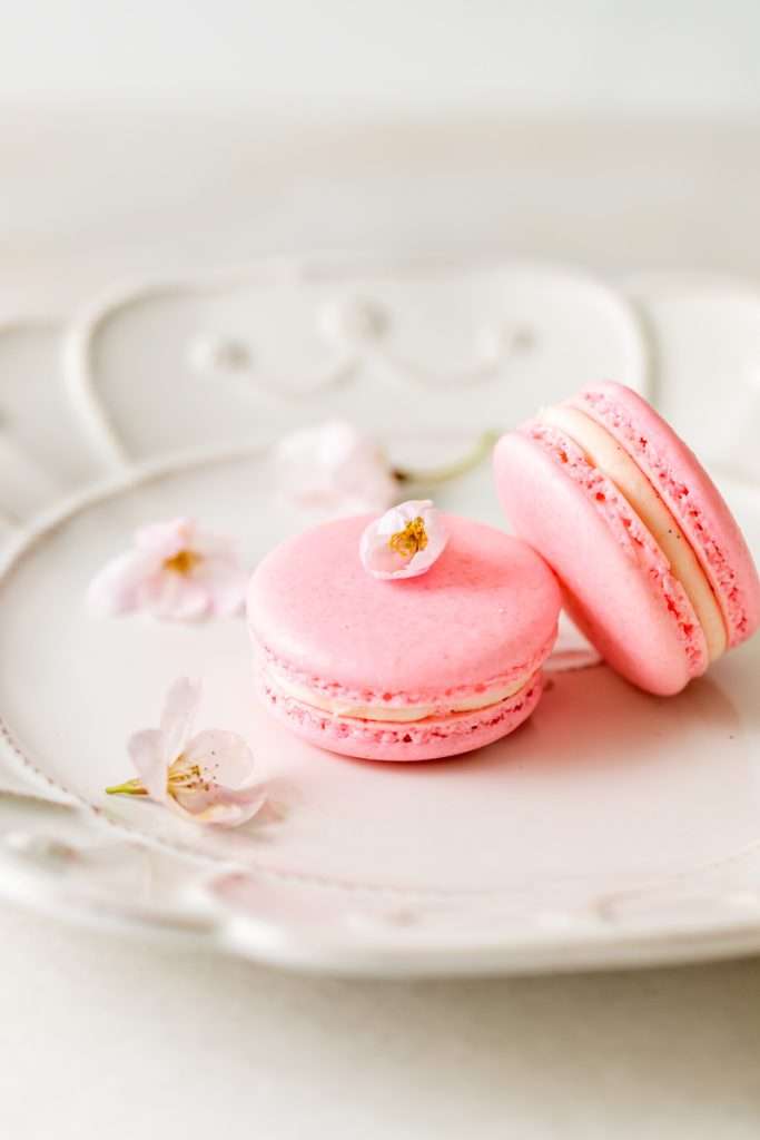 Spring macaron recipe filled with Sakura cherry blossom frosting and a fresh strawberry center. Dairy Free, Gluten Free and the perfect macaron and treat for spring.