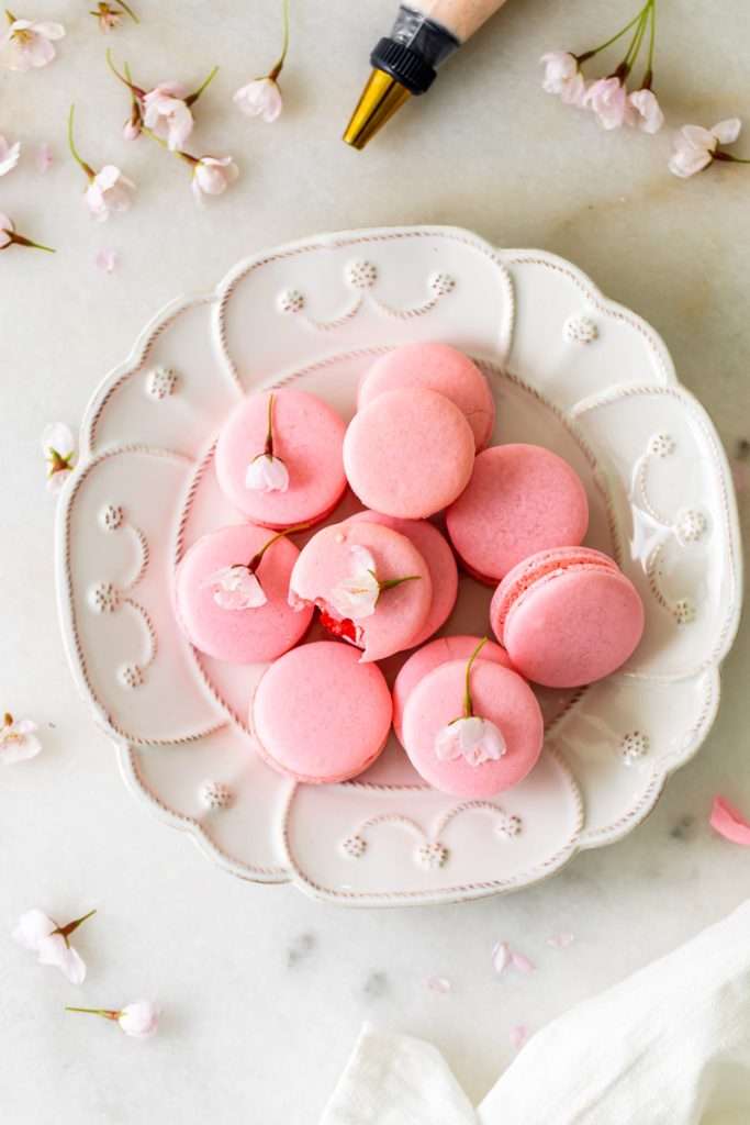 Spring macaron recipe filled with Sakura cherry blossom frosting and a fresh strawberry center. Dairy Free, Gluten Free and the perfect macaron and treat for spring.