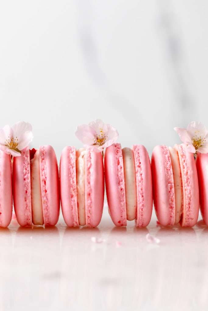 Spring macaron recipe filled with Sakura cherry blossom frosting and a fresh strawberry center. Dairy Free, Gluten Free and the perfect macaron and treat for spring.