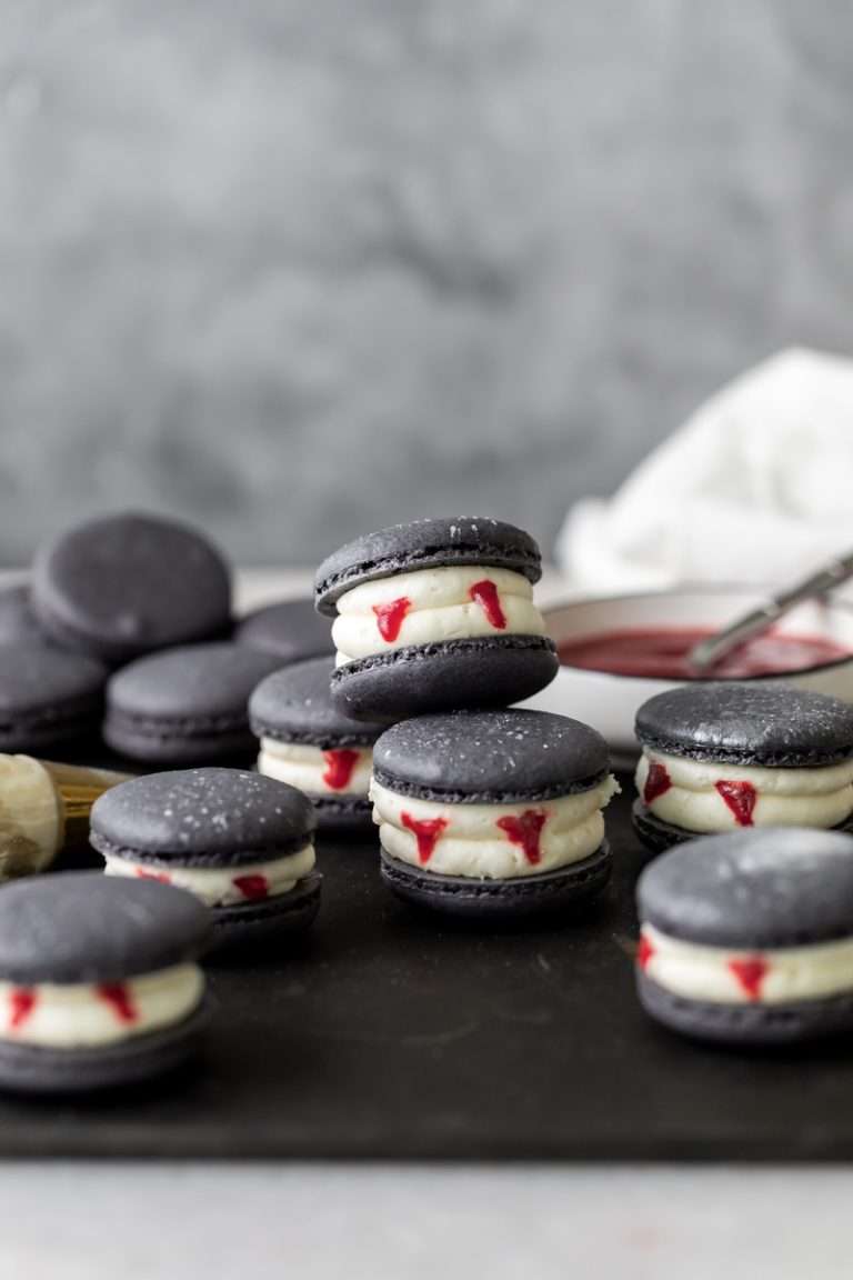 Easy Vampire decorated macarons for Halloween, with black cocoa shells, vanilla bean frosting and strawberry jam. A spooky sweet macaron for the fall season! Dairy free & Gluten free